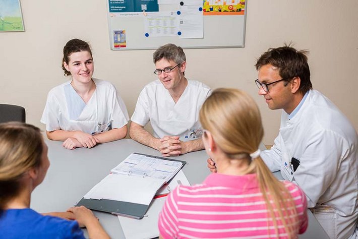 Teambesprechung zwischen Pflegekräften und Ärzten. Zum Wohle des Patienten wird interdisziplinär eng zusammen gearbeitet.