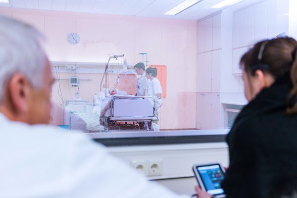 Praxisanleiter steuern vom Regie-Raum aus Szenarien im Übungs-Krankenzimmer mit High-Tech-Puppe. So werden die Krankenpflegeschüler praxisnah auf den ersten Patientenkontakt vorbereitet.