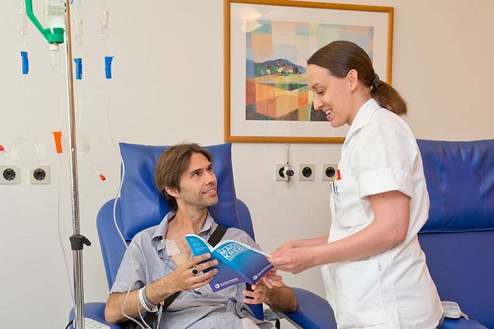Eine Pflegekraft erklärt einem Krebs-Patienten die Therapie.
